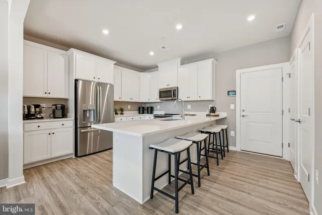a kitchen with stainless steel appliances a table chairs and a refrigerator
