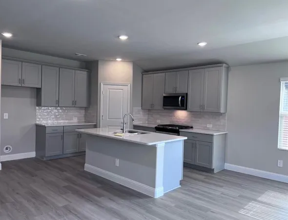 a kitchen with stainless steel appliances granite countertop a stove top oven a sink dishwasher and a refrigerator with wooden floor