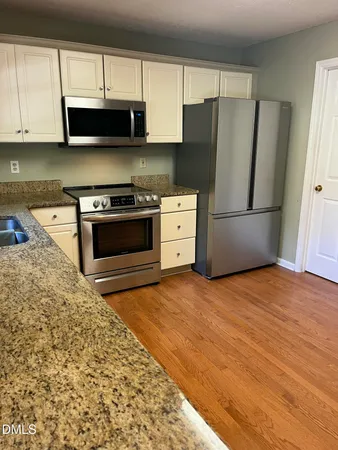 a kitchen with a refrigerator stove and white cabinets