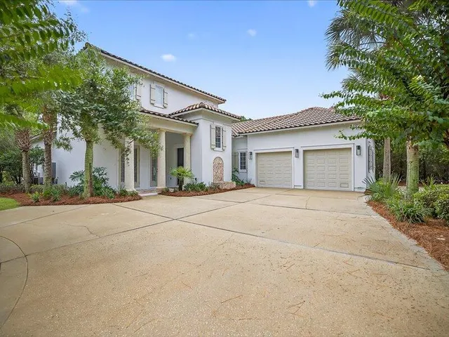 a view of white house with a yard and palm trees