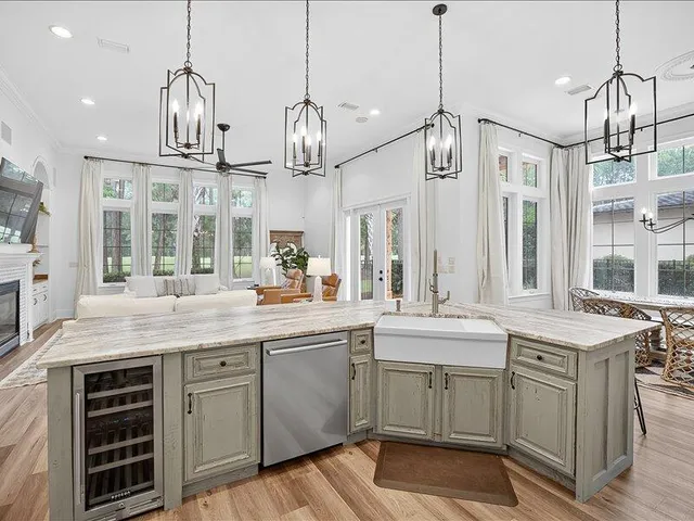 a kitchen with stainless steel appliances granite countertop a stove a sink dishwasher a refrigerator and white cabinets with wooden floor