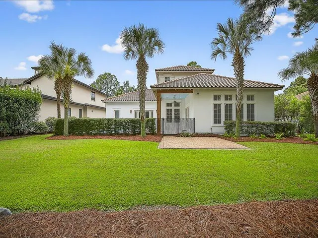 a front view of a house with a yard and palm trees