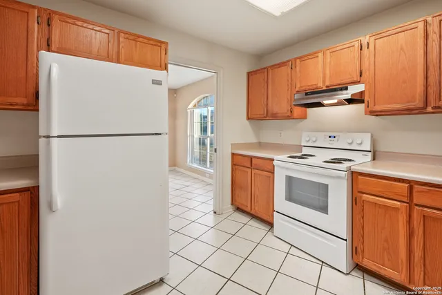 a white refrigerator freezer and a stove sitting inside of a kitchen with granite countertop stainless steel appliances