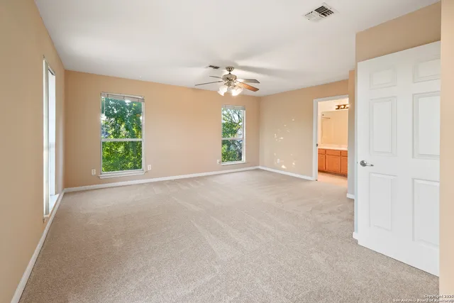 an empty room with windows and fan