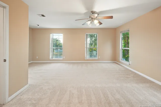 an empty room with windows and chandelier fan