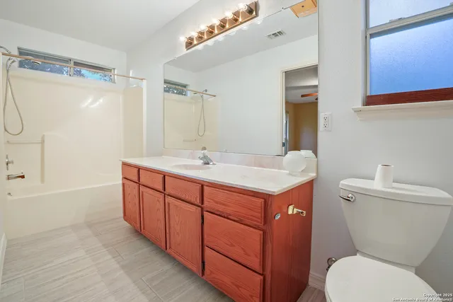 a bathroom with a granite countertop sink mirror vanity and toilet