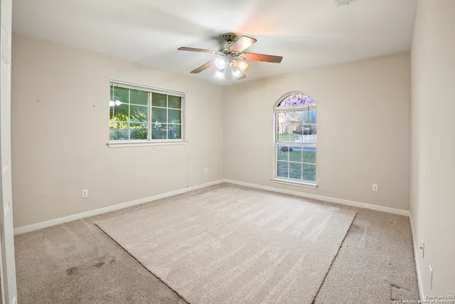 an empty room with windows and chandelier fan