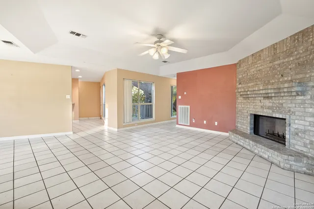 a view of an empty room with window and chandelier fan