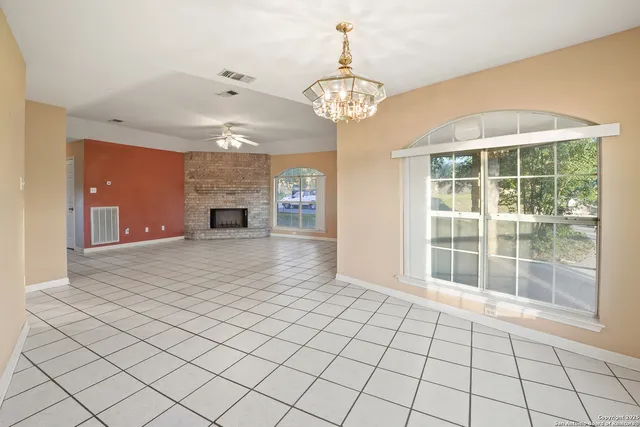 a view of an empty room with a window and chandelier