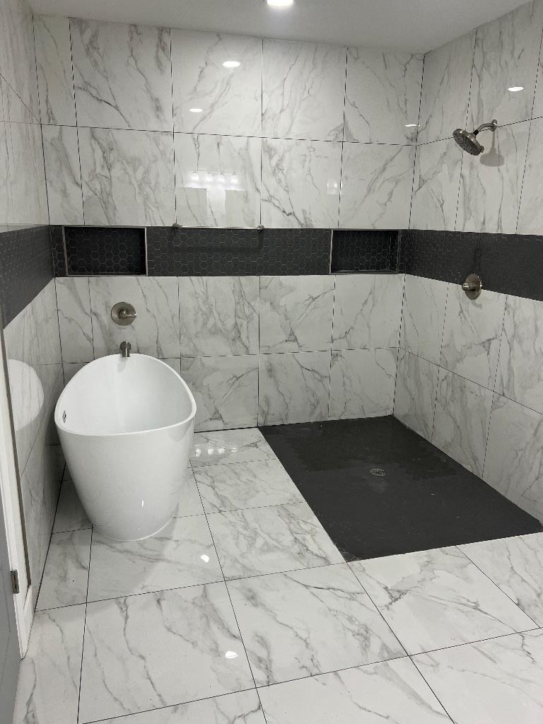 Full bath featuring marble look tile flooring and a shower