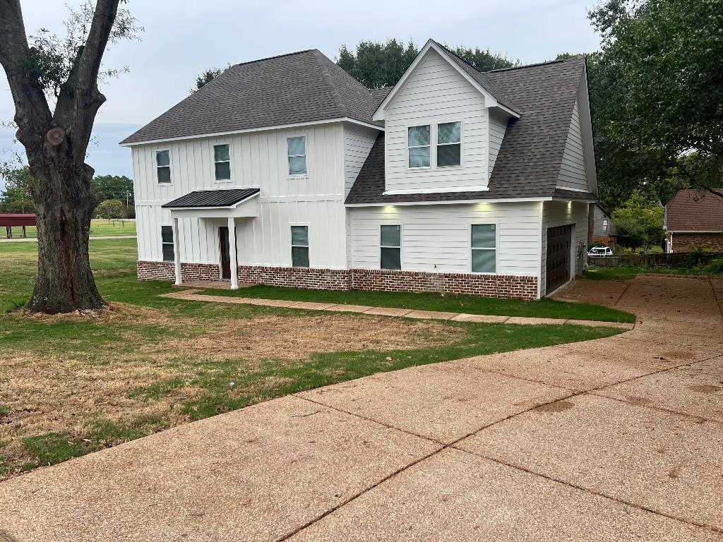 56 South Sanga Road Memphis, TN 38018 - Photo 20 of 23 View of front facade featuring a shingled roof, a front lawn, driveway, board and batten siding, and brick siding