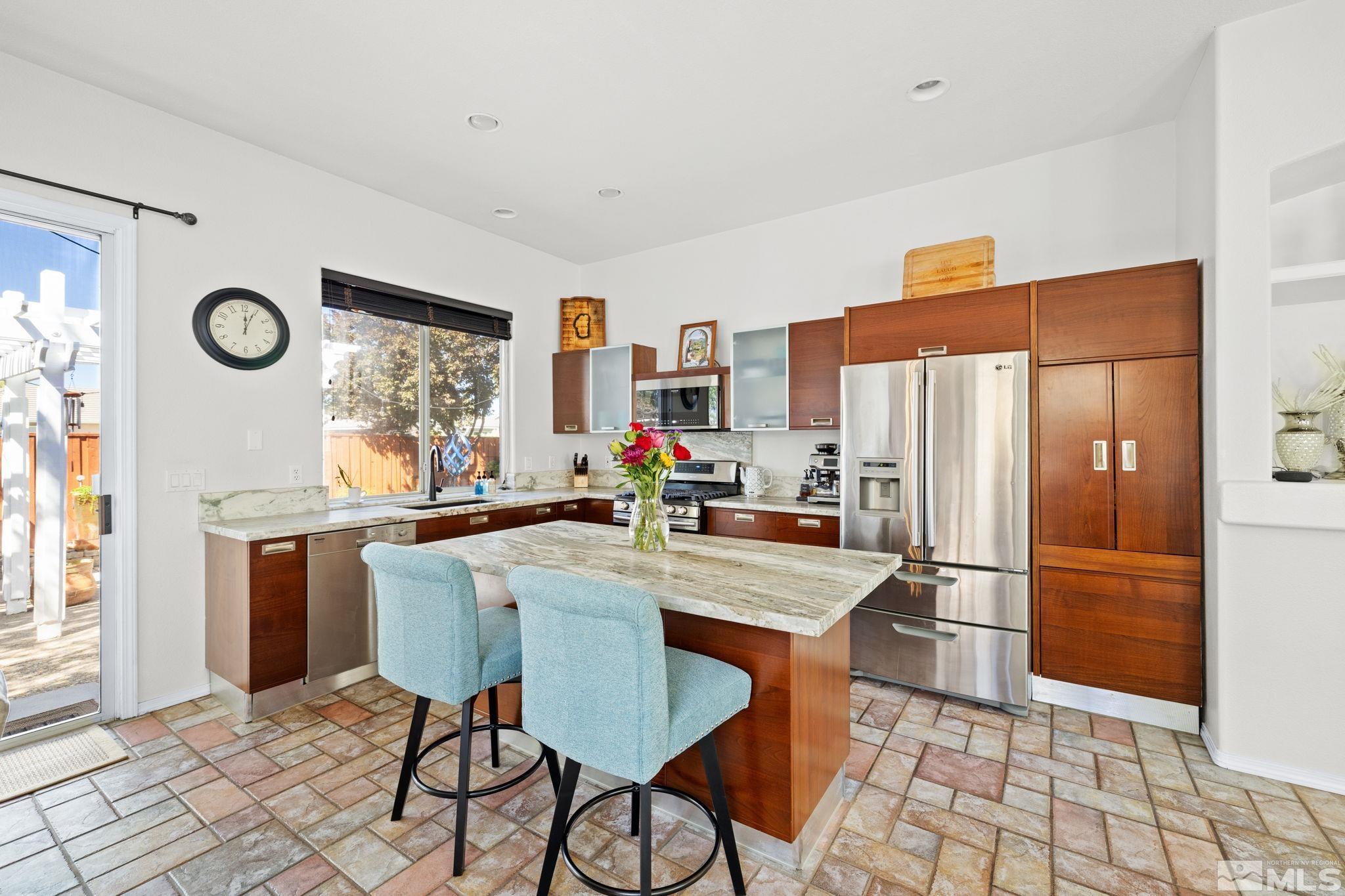 9873 Northrup Drive Reno, NV 89521 - Photo 8 of 24 a kitchen with stainless steel appliances a refrigerator a stove a dining table and chairs with wooden floor