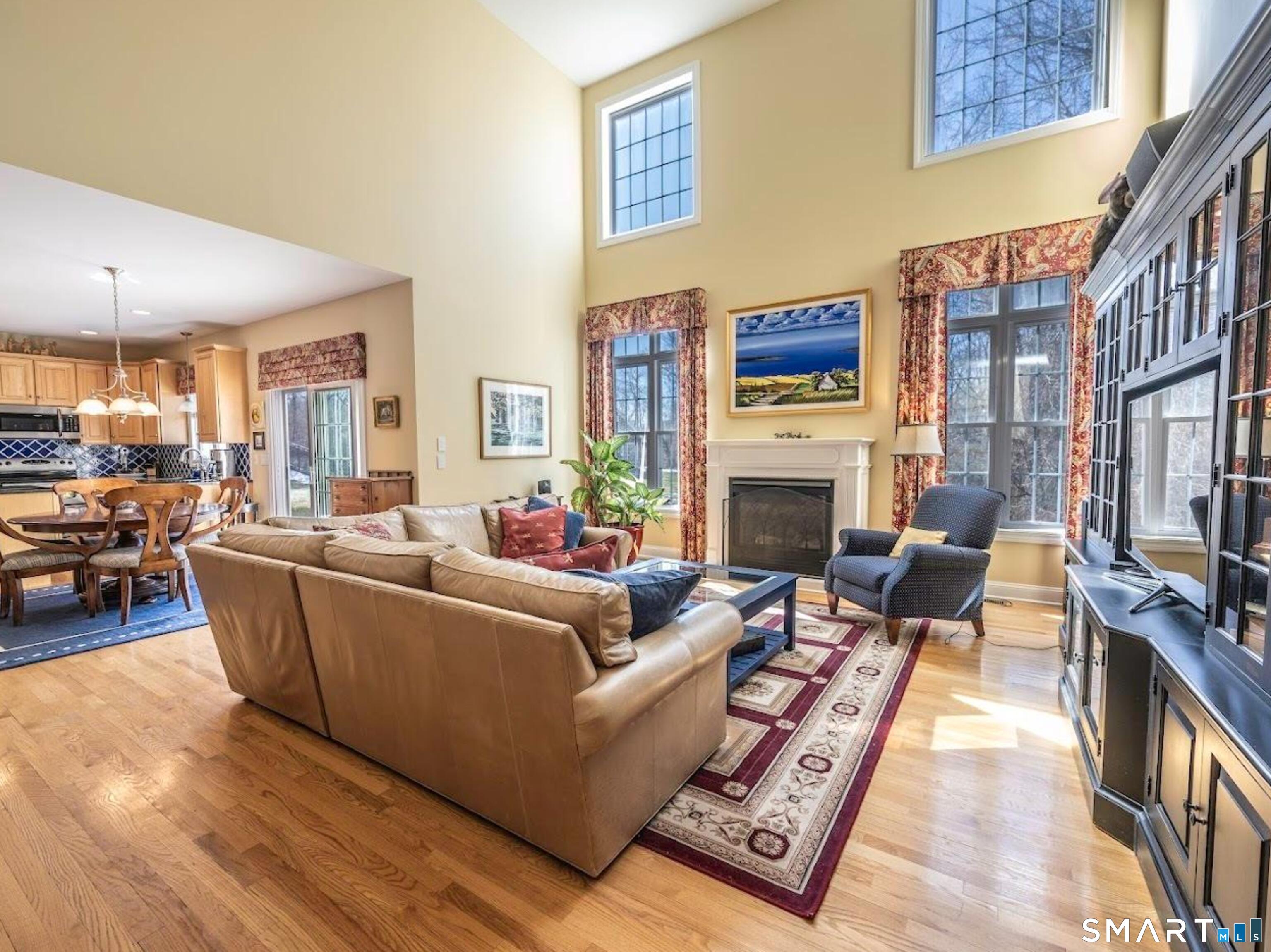22 R Olde Yankee Way Durham, CT 06422 - Photo 7 of 29 Sun-filled open living space featuring soaring cathedral ceilings, upper windows, hardwood floors, fireplace, and seamless flow to kitchen and dining area.