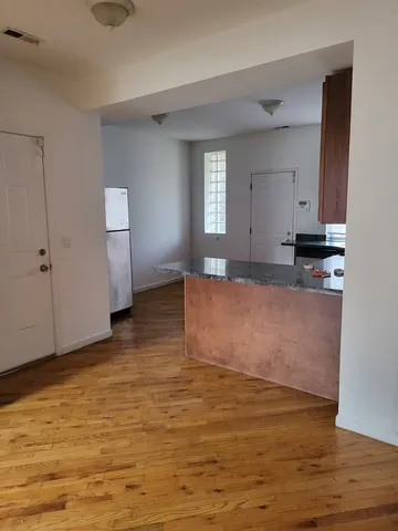 a view of kitchen and empty room with wooden floor