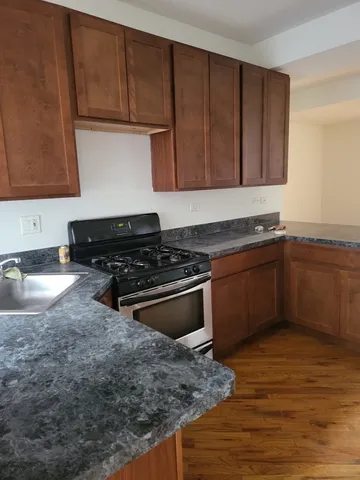 a kitchen with granite countertop a sink a stove and cabinets