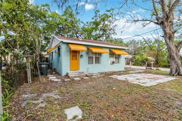 a backyard of a house with large trees and brick wall