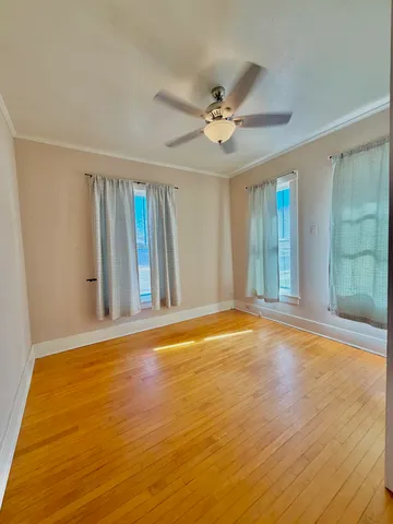 a view of an empty room with window and wooden floor