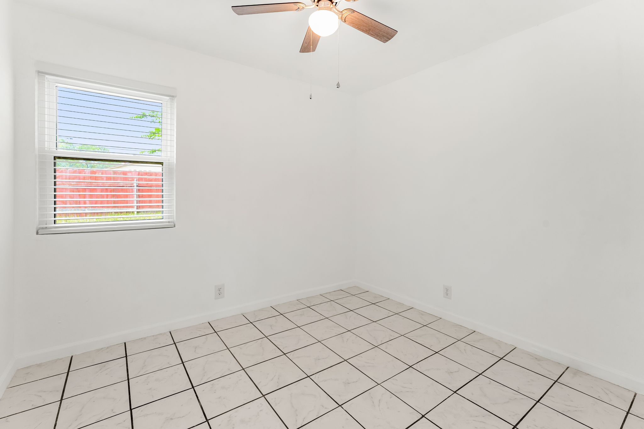 2501 Teri Road, Unit B Austin, TX 78744 - Photo 13 of 21 Bright room featuring white tile flooring with contrasting grout, a window with horizontal blinds, and a ceiling fan with integrated lighting