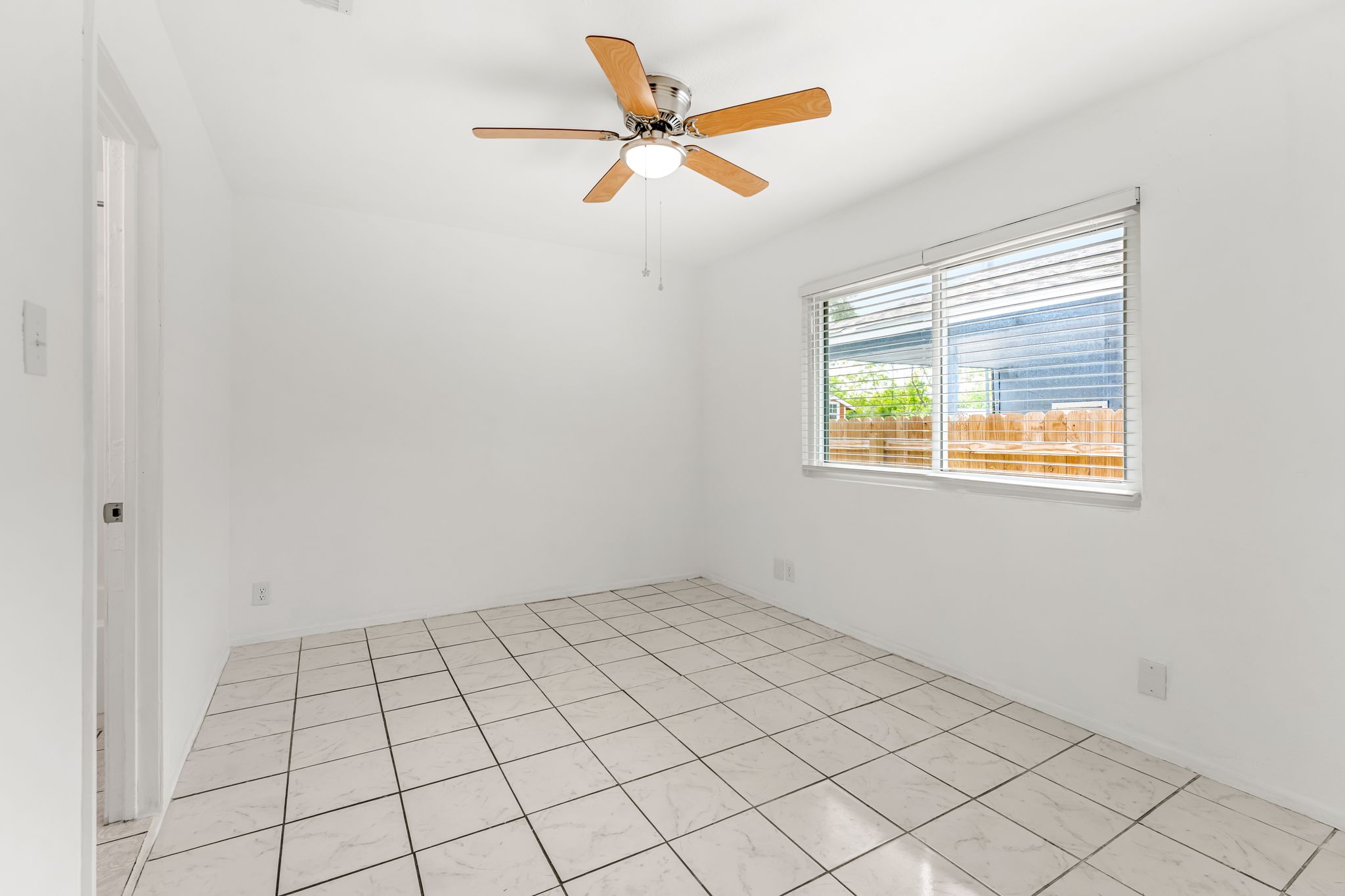 2501 Teri Road, Unit B Austin, TX 78744 - Photo 14 of 21 White tile flooring, a large window with horizontal blinds, and a ceiling fan with light fixture