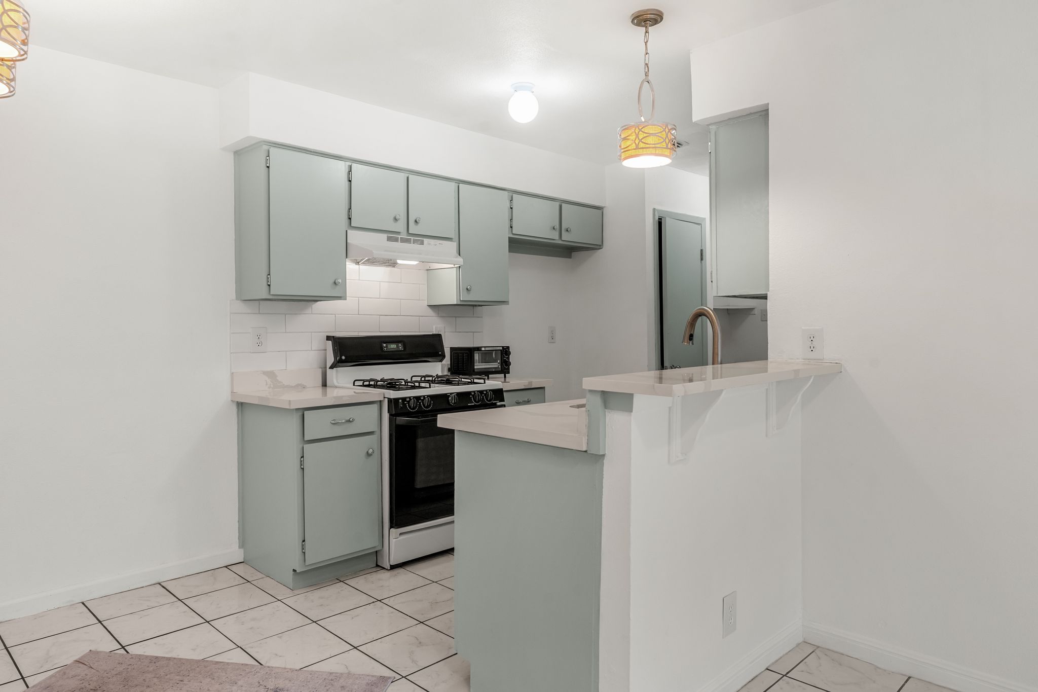 2501 Teri Road, Unit B Austin, TX 78744 - Photo 2 of 21 Kitchen featuring light blue cabinetry, subway tile backsplash, white tile flooring, light-toned countertops, and a breakfast bar with a gooseneck faucet