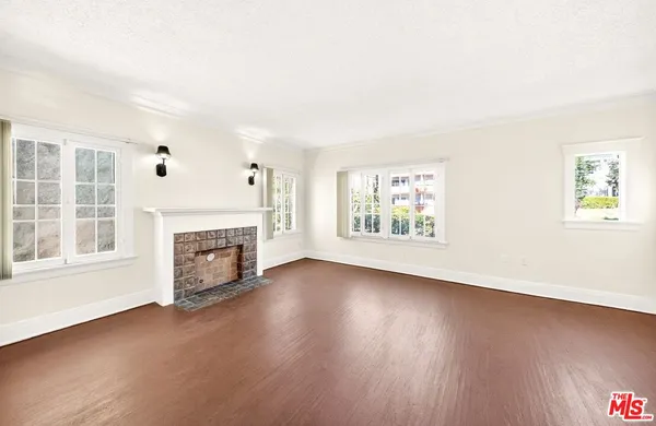 an empty room with windows fireplace and wooden floor