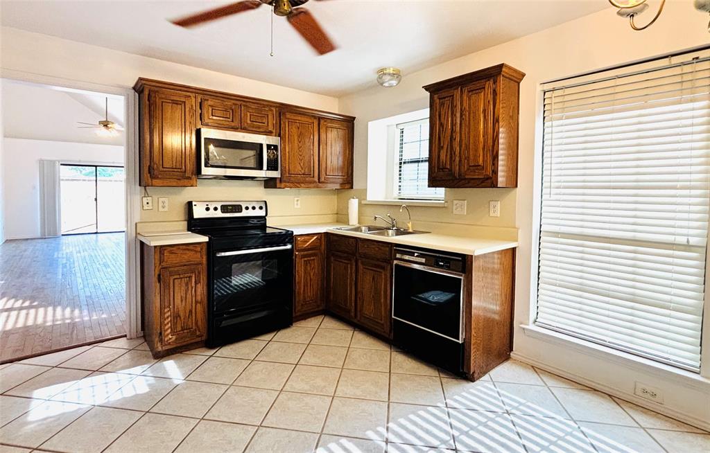 Kitchen featuring wood cabinetry, white countertops, tile flooring, and a stainless steel over-the-range microwave