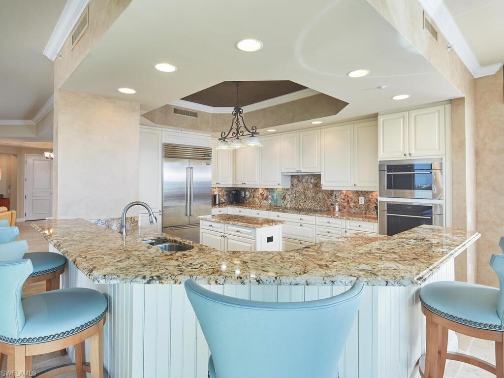 23750 Via Trevi Way, Unit 2001 Estero, FL 34134 - Photo 13 of 26 Kitchen featuring ornamental molding, a breakfast bar, a raised ceiling, light stone countertops, and stainless steel appliances
