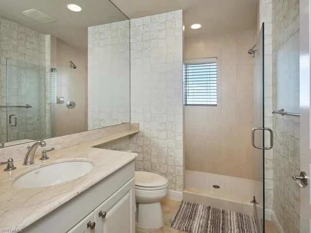 a bathroom with a granite countertop sink a toilet and shower