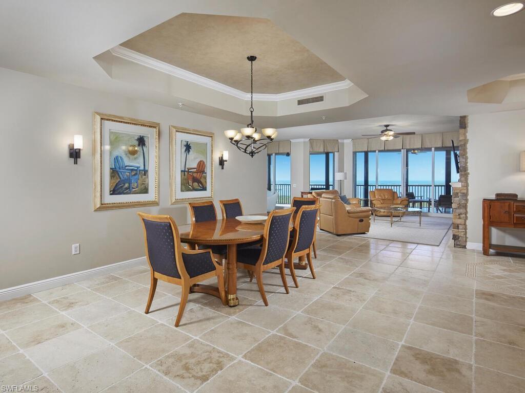 23750 Via Trevi Way, Unit 2001 Estero, FL 34134 - Photo 8 of 26 Dining room with crown molding, a chandelier, a tray ceiling, ceiling fan, and light tile patterned floors
