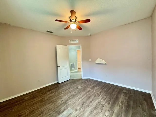 a view of an empty room with window and chandelier fan