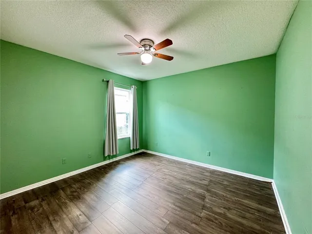an empty room with wooden floor ceiling fan and window