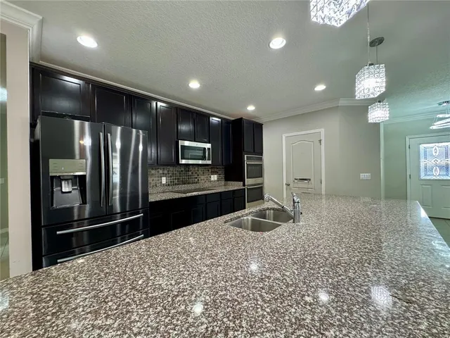 a kitchen with stainless steel appliances kitchen island granite countertop a refrigerator and a sink