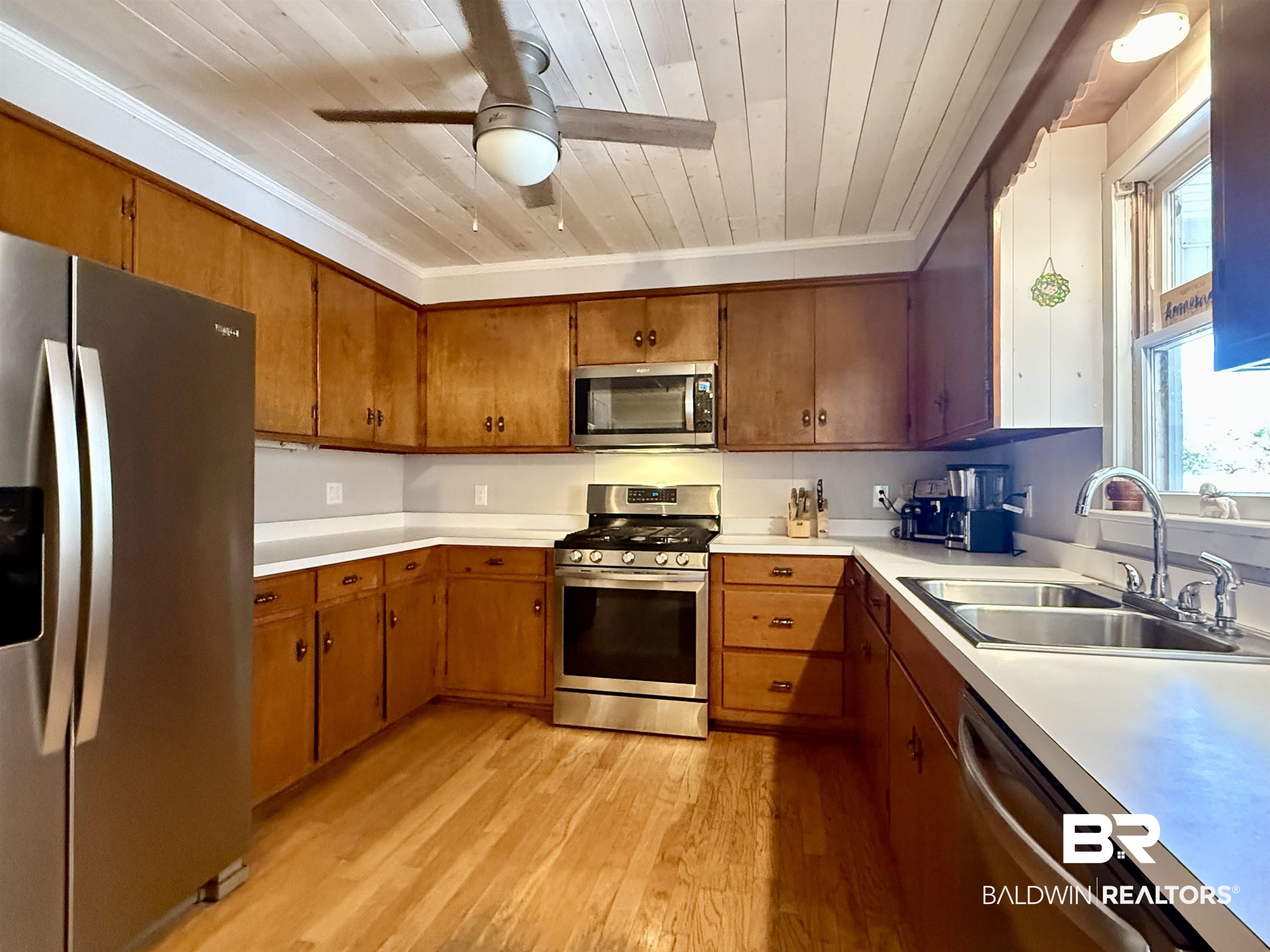 2785 Appleton Road Brewton, AL 36426 - Photo 11 of 28 Kitchen with stainless steel appliances, light countertops, brown cabinetry, light wood-style floors, and a ceiling fan