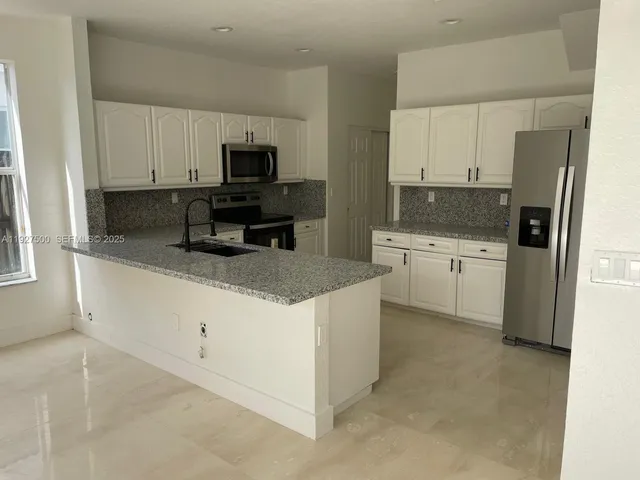 a kitchen with white cabinets and stainless steel appliances