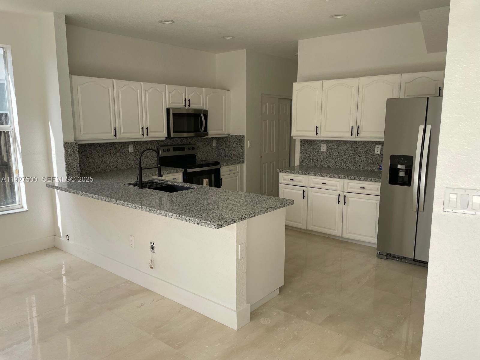 15964 Southwest 139th Street Miami, FL 33196 - Photo 5 of 22 a kitchen with white cabinets and stainless steel appliances