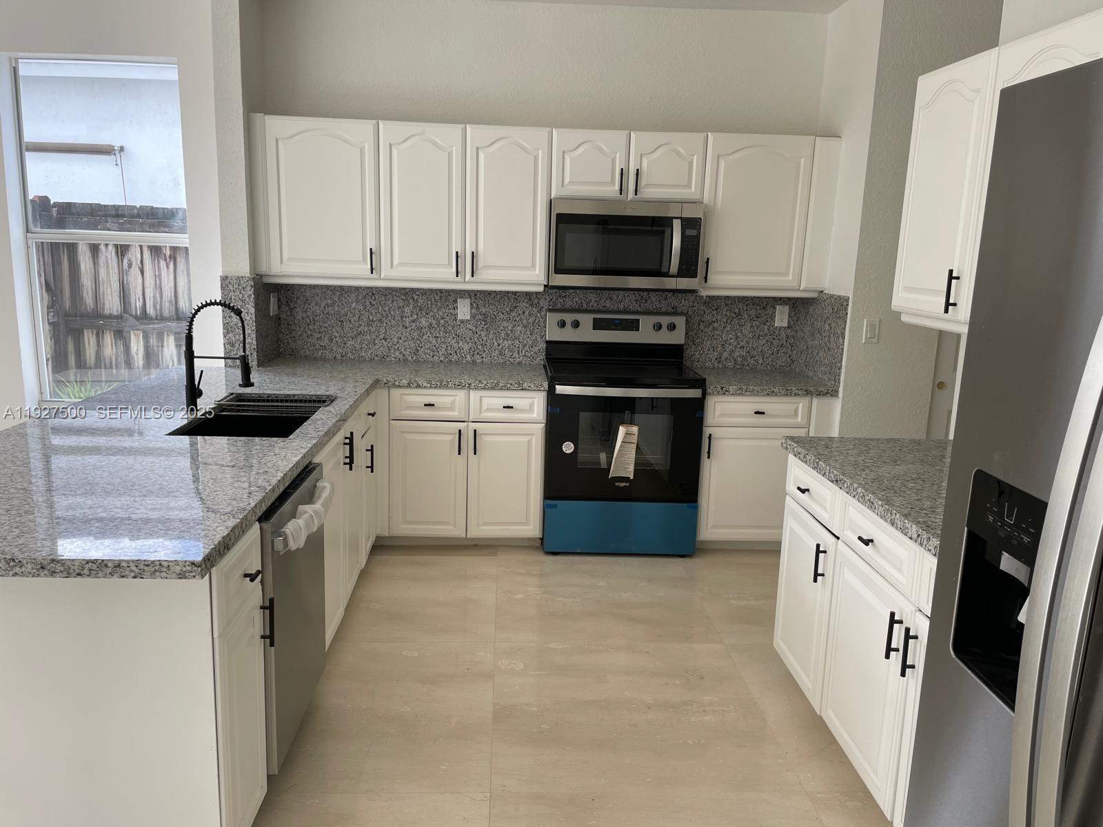 15964 Southwest 139th Street Miami, FL 33196 - Photo 6 of 22 a kitchen with stainless steel appliances granite countertop a sink stove and refrigerator