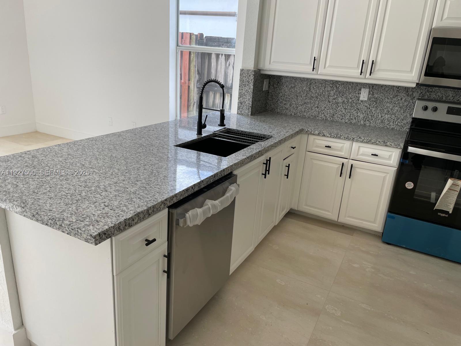 15964 Southwest 139th Street Miami, FL 33196 - Photo 7 of 22 a kitchen with granite countertop a sink and cabinets