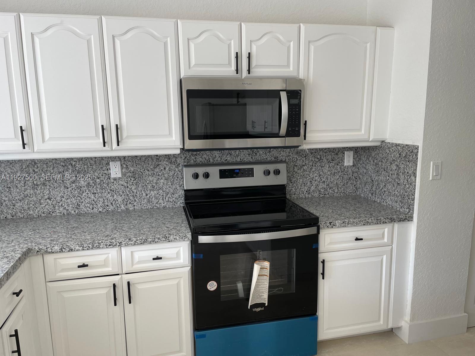 15964 Southwest 139th Street Miami, FL 33196 - Photo 9 of 22 a kitchen with white cabinets and black appliances