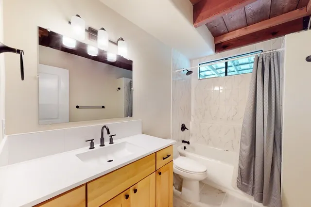 a bathroom with a toilet a sink a tub and mirror