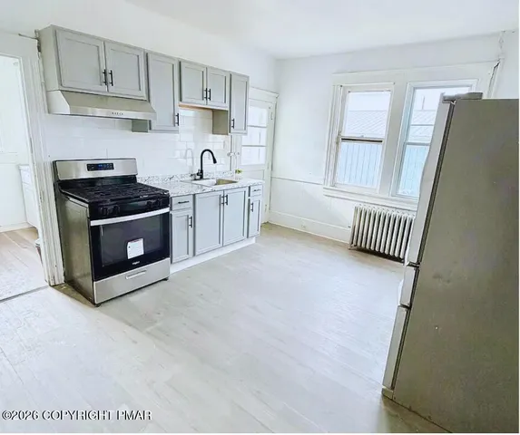 a kitchen with stainless steel appliances a stove a sink and white cabinets