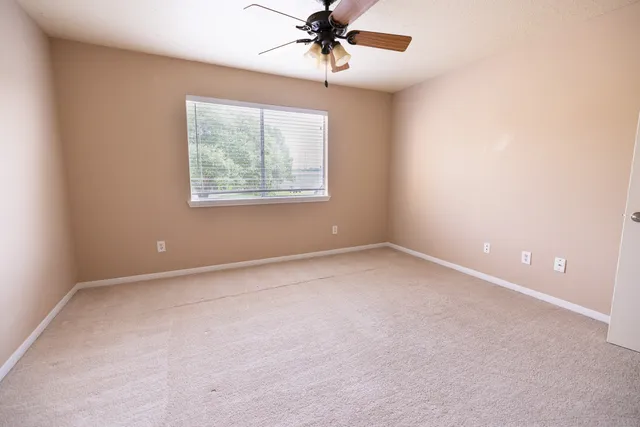 an empty room with windows and fan
