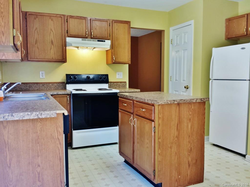 11414 Gold Pan Road Charlotte, NC 28215 - Photo 9 of 24 a kitchen with granite countertop a refrigerator a stove and wooden cabinets