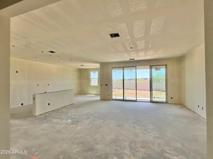 an empty room with chandelier fan and windows