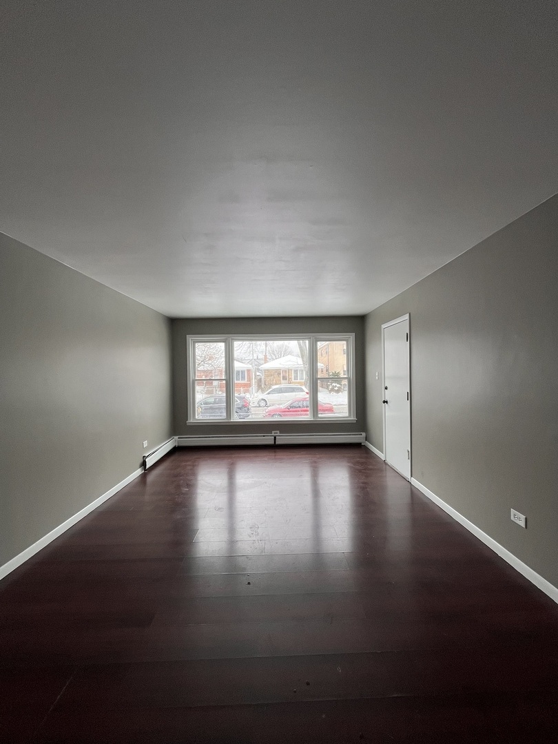 6138 South Kilpatrick Avenue, Unit 1 Chicago, IL 60629 - Photo 4 of 11 an empty room with wooden floor and windows