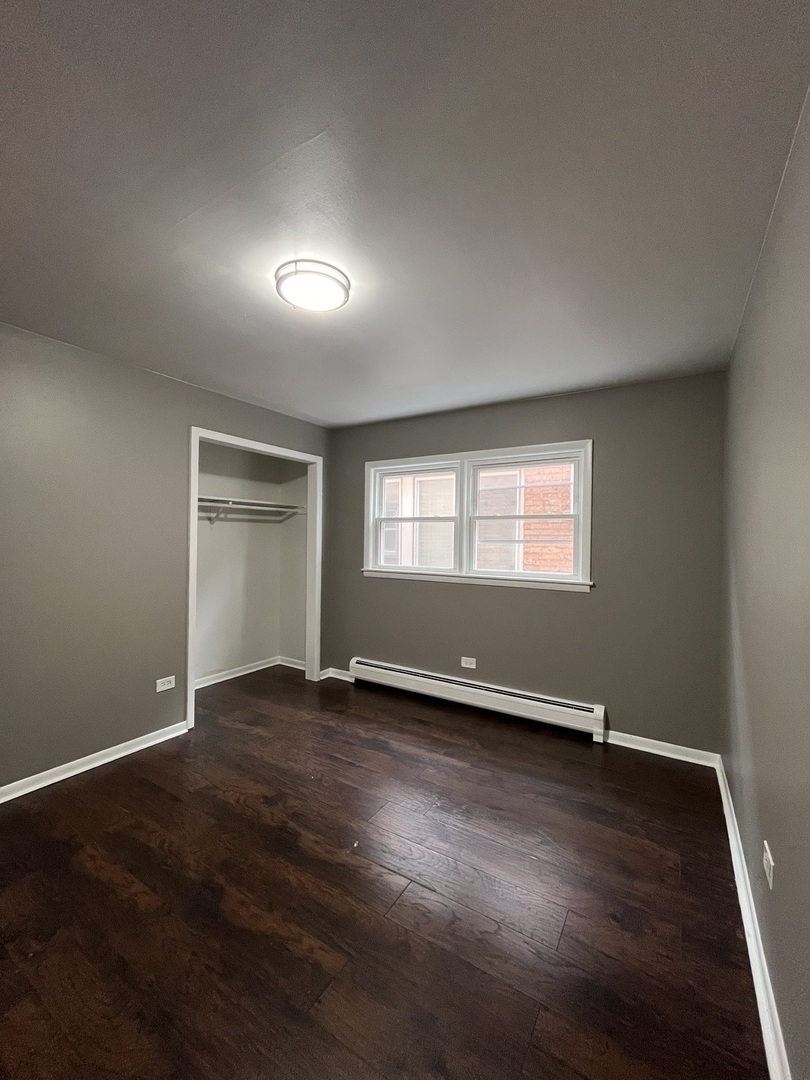6138 South Kilpatrick Avenue, Unit 1 Chicago, IL 60629 - Photo 7 of 11 an empty room with wooden floor and windows