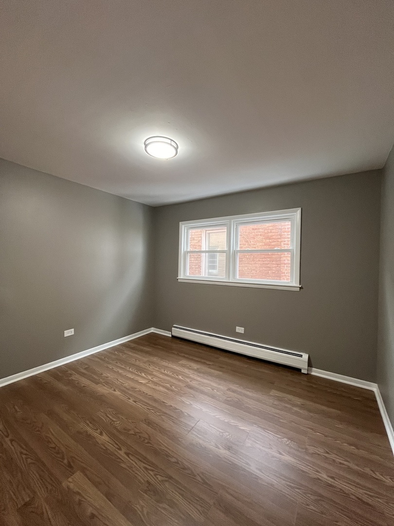 6138 South Kilpatrick Avenue, Unit 1 Chicago, IL 60629 - Photo 8 of 11 an empty room with wooden floor and windows