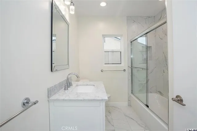 a bathroom with a granite countertop sink a mirror and shower