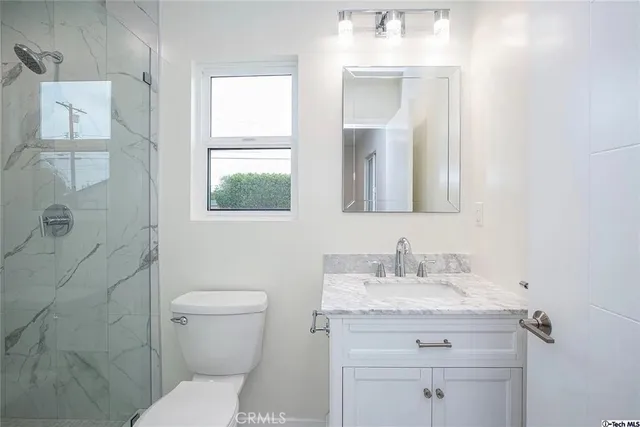 a bathroom with a granite countertop toilet a sink and a mirror