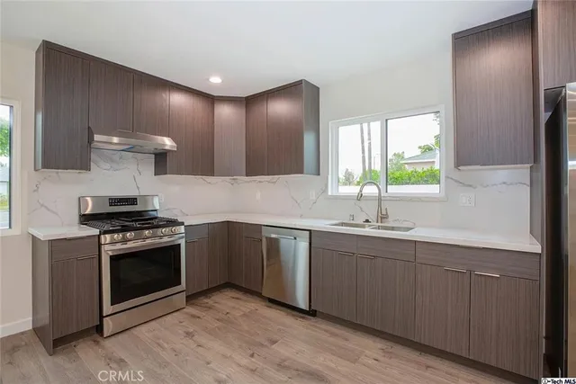 a kitchen with stainless steel appliances a sink stove and cabinets