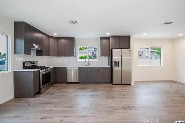 a kitchen with stainless steel appliances a refrigerator and a stove top oven